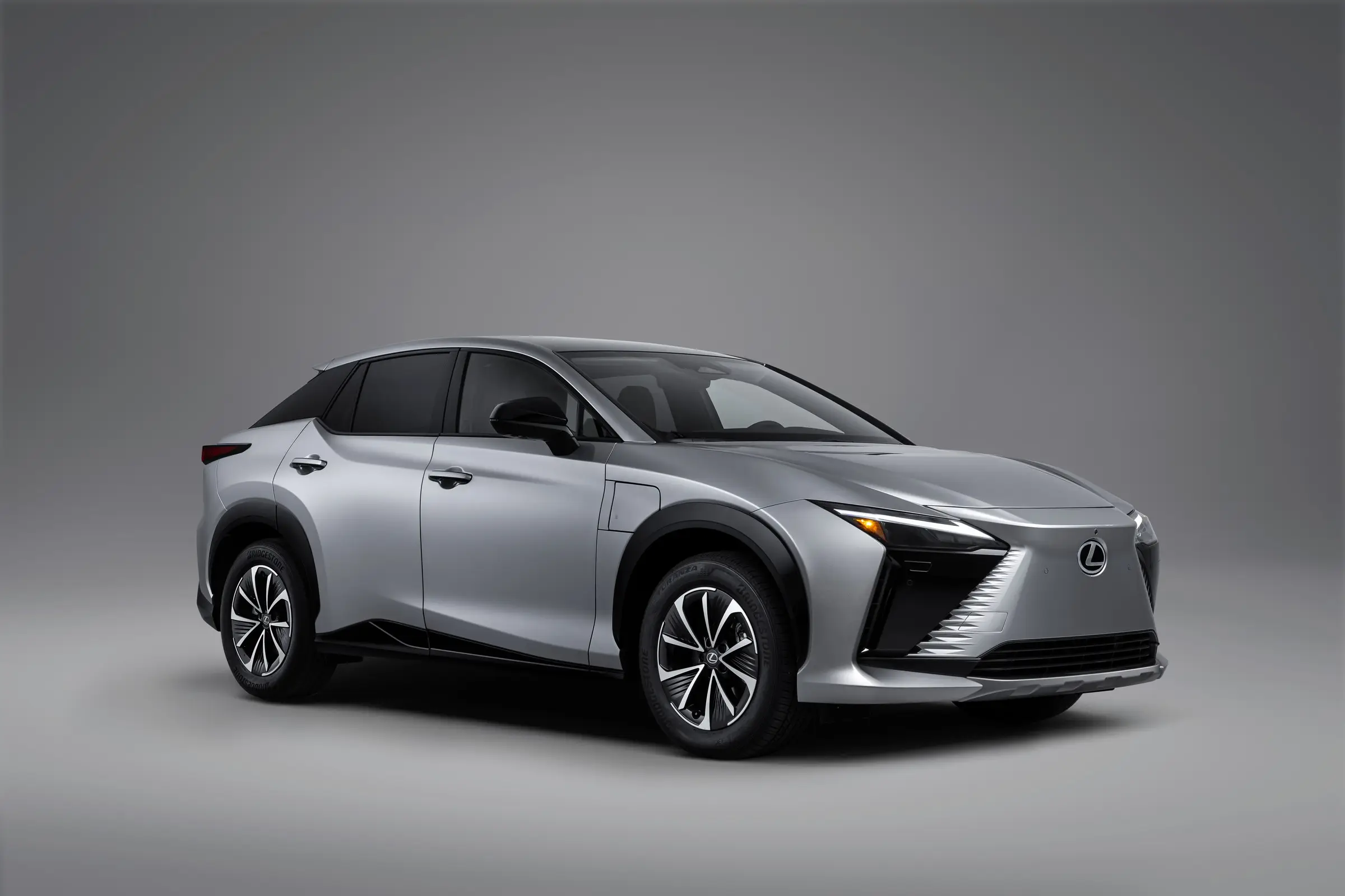A silver Lexus RZ 350e photographed from the front three-quarter in a studio